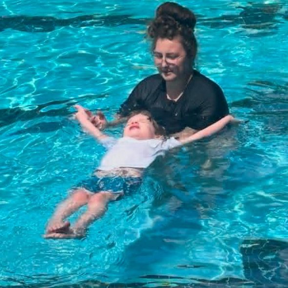 Swim instructor, Keara in the pool with a boy student age 5 who is floating on his back like a starfish