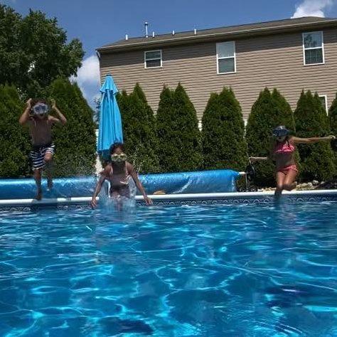 3 children jumping into the pool together and smiling